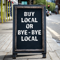 A sign that says, "Buy local or bye-bye local"